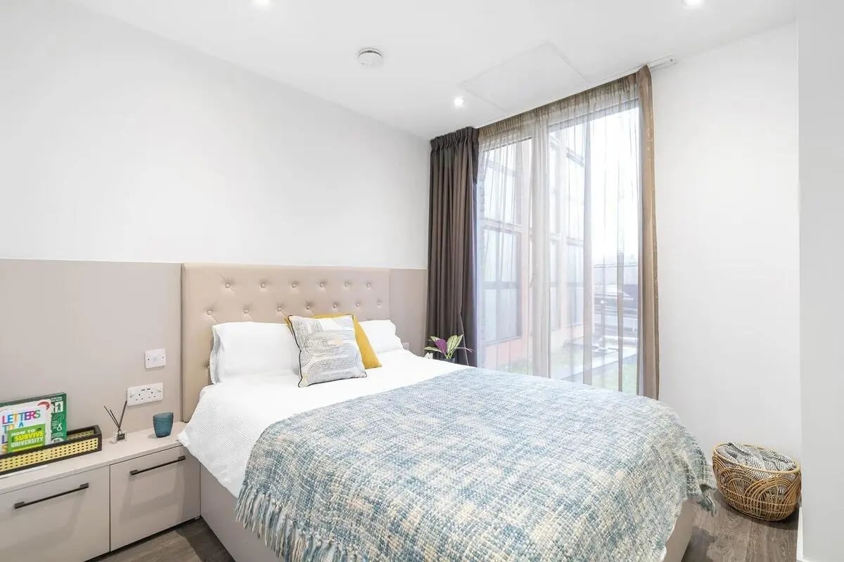 Bed with patterned throw bedside table basket Bedroom at Canvas Coventry City Club in Coventry Student Accommodation
