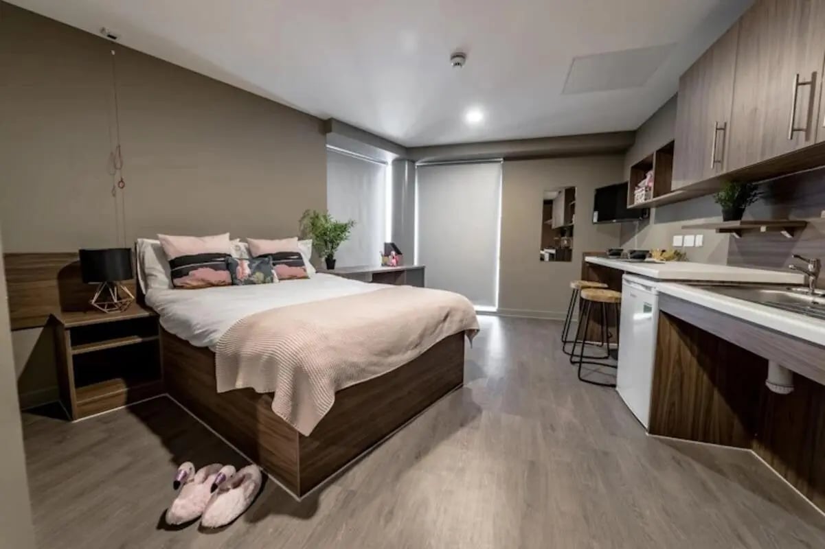 Bed bedside table plant and kitchen studio apartment at Scotway House in Glasgow Student Accommodation