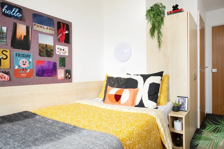 Bed with yellow duvet and framed posters bedroom at Clodien House in Cardiff Student Accommodation