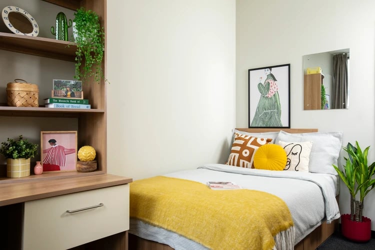 Bed with yellow throw and decorative pillows bedroom at Favell House in Bristol Student Accommodation