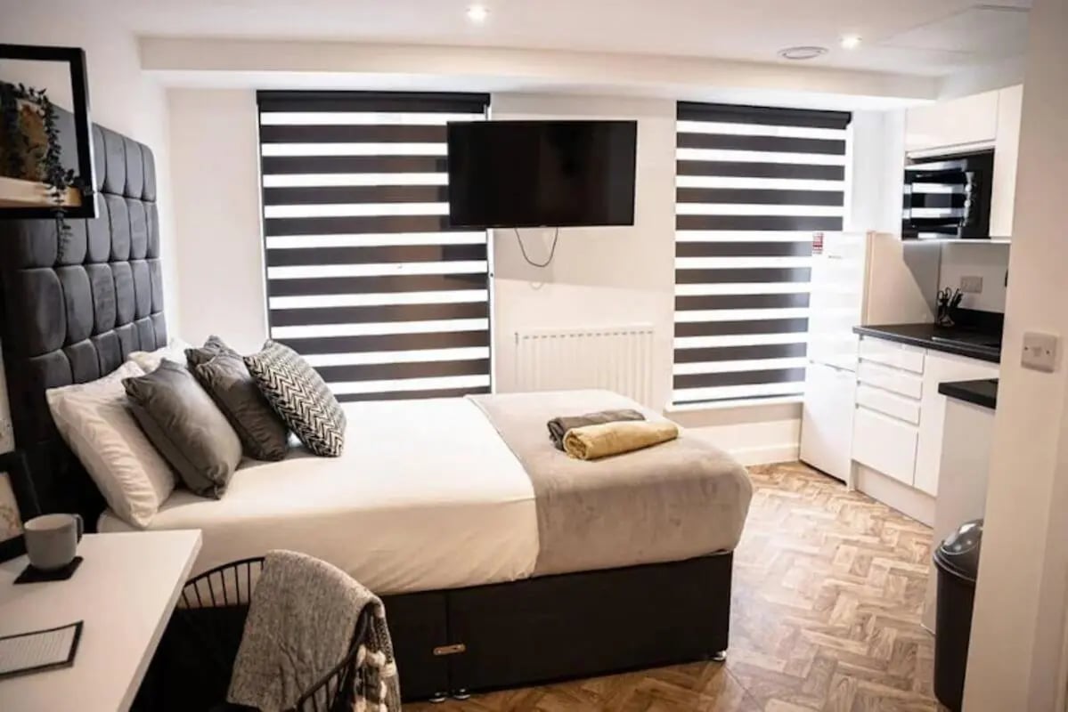 Bed with pillows desk television and kitchenette studio at Bridge Street Studios in Birmingham Student Accommodation