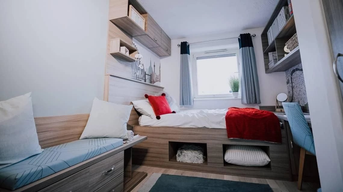 Bed with red blanket desk chair shelves bedroom at Manna Ash House in London Student Accommodation