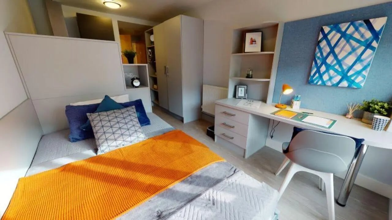 Bed with orange throw desk with lamp bedroom at iQ Hoxton in London Student Accommodation