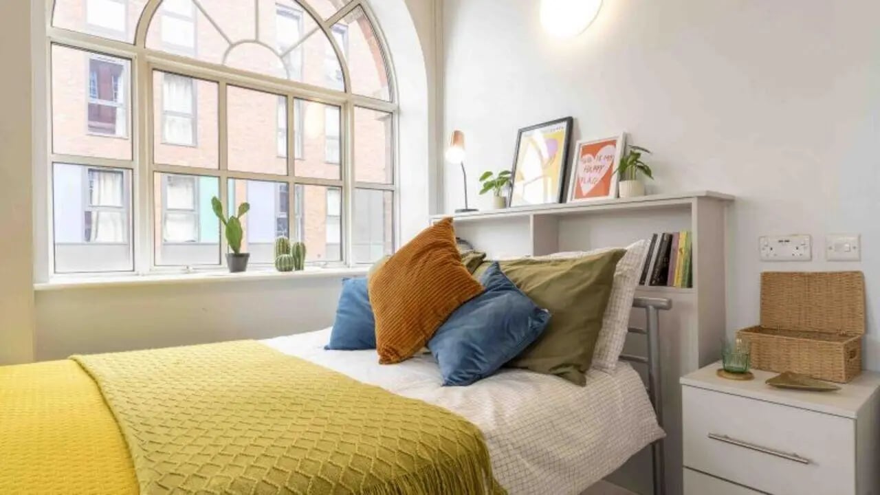 Bed with yellow blanket and pillows Bedroom at iQ Bloomsbury in London Student Accommodation