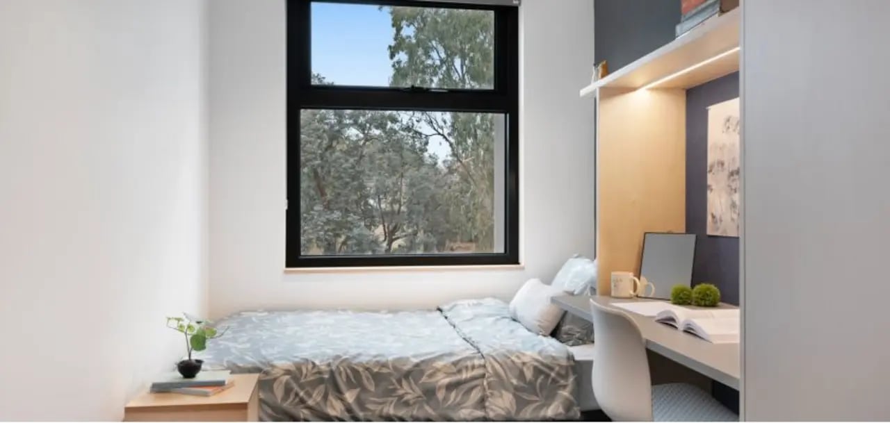 Bed and desk with books and mug Bedroom at La Trobe University - North and South Apartments in Melbourne Student Accommodation