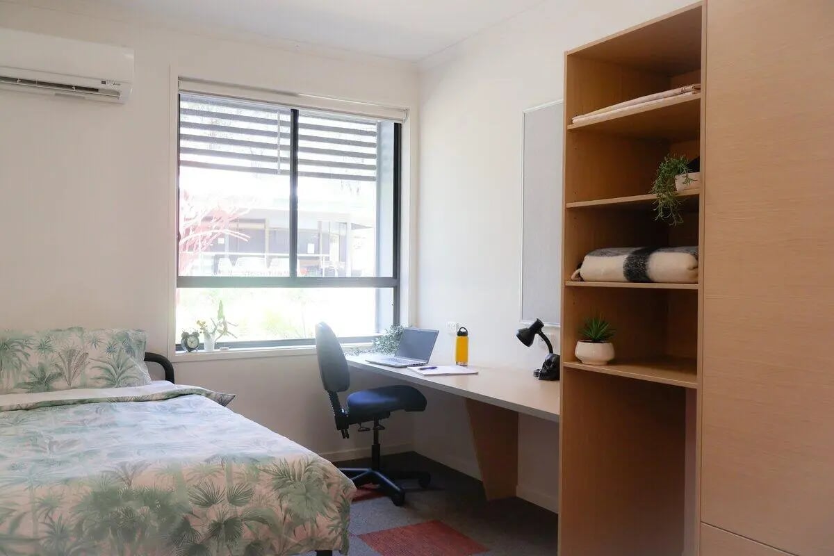 Bed desk chair laptop and shelving unit bedroom at La Trobe University - Hillside Apartments in Melbourne Student Accommodation