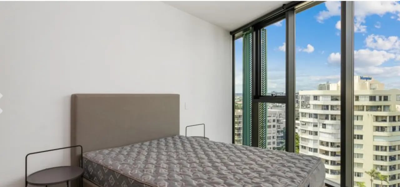 Bed with grey headboard side tables large window bedroom at Realm Kangaroo Point in Brisbane Student Accommodation
