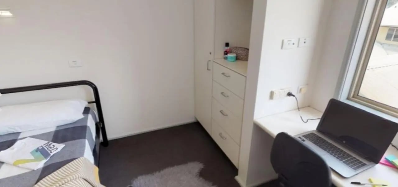 Bed wardrobe desk with laptop and chair bedroom at Western Sydney University Penrith Village in Sydney Student Accommodation