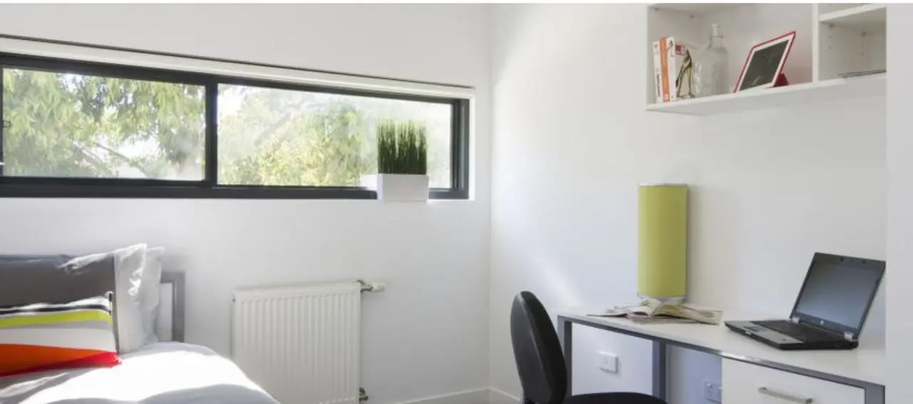 Bed laptop desk shelf lamp and window bedroom at Western Sydney University Campbelltown Village in Sydney Student Accommodation