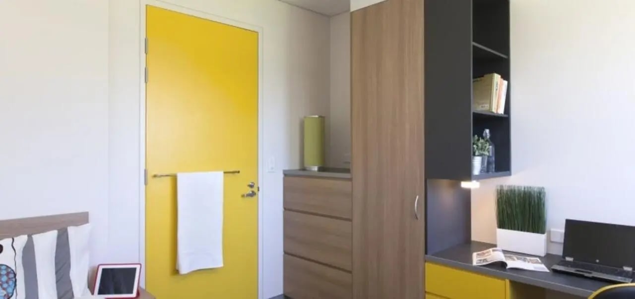 Bed with tablet and yellow door study desk living room at Western Sydney University Penrith Village in Sydney Student Accommodation