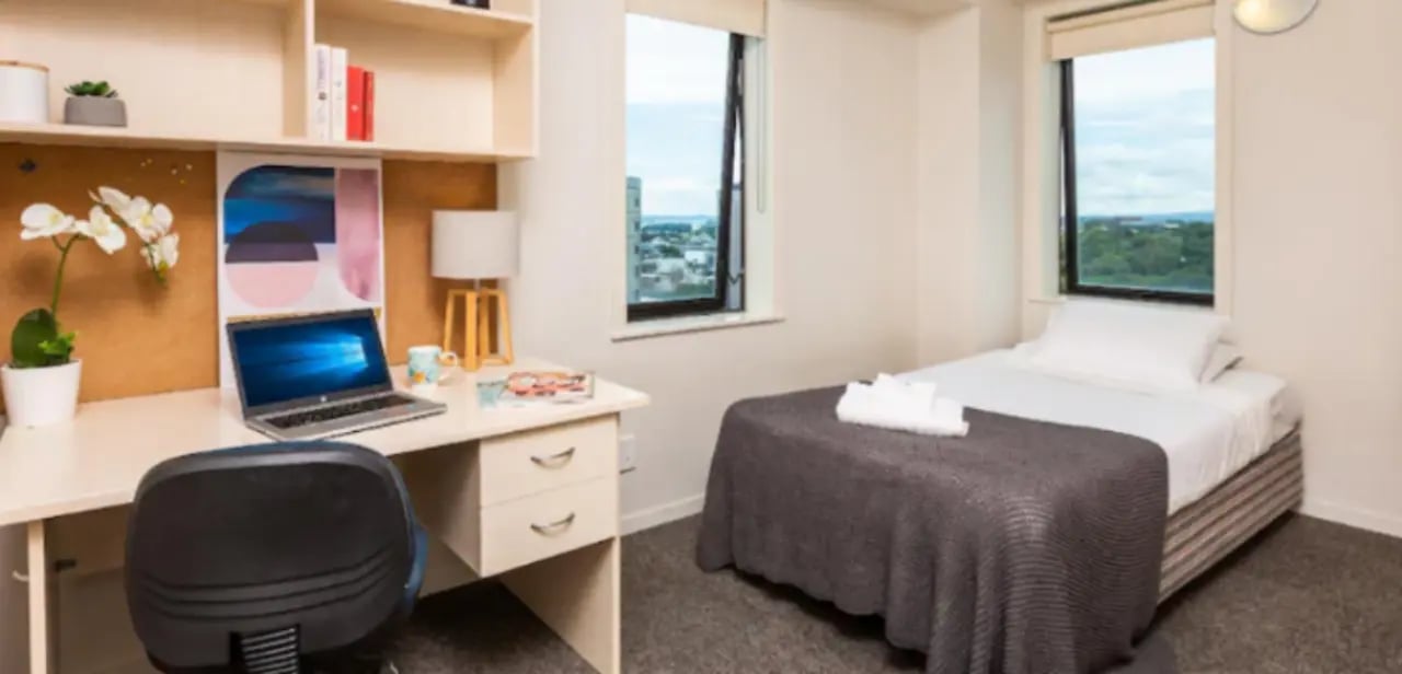 Desk with laptop and bed bedroom at Wellesley Apartments in Auckland Student Accommodation