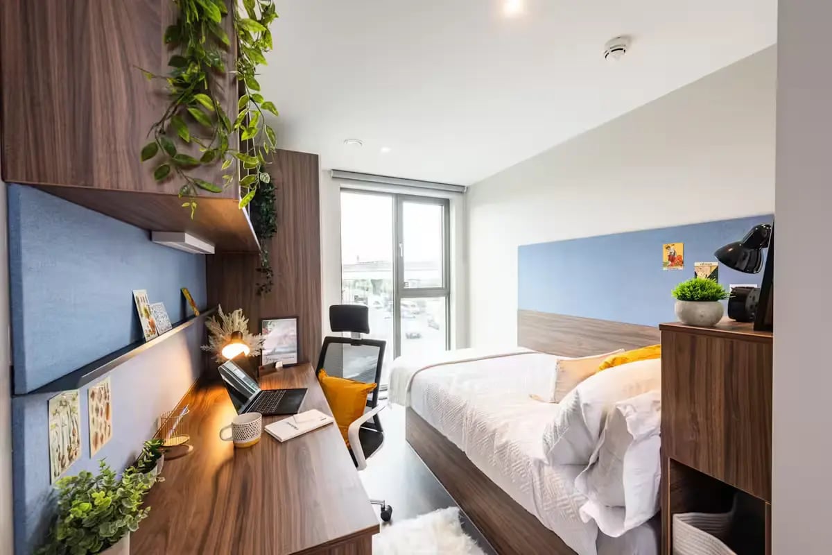 Desk with laptop bed and plants bedroom at Nelson Place in Belfast Student Accommodation