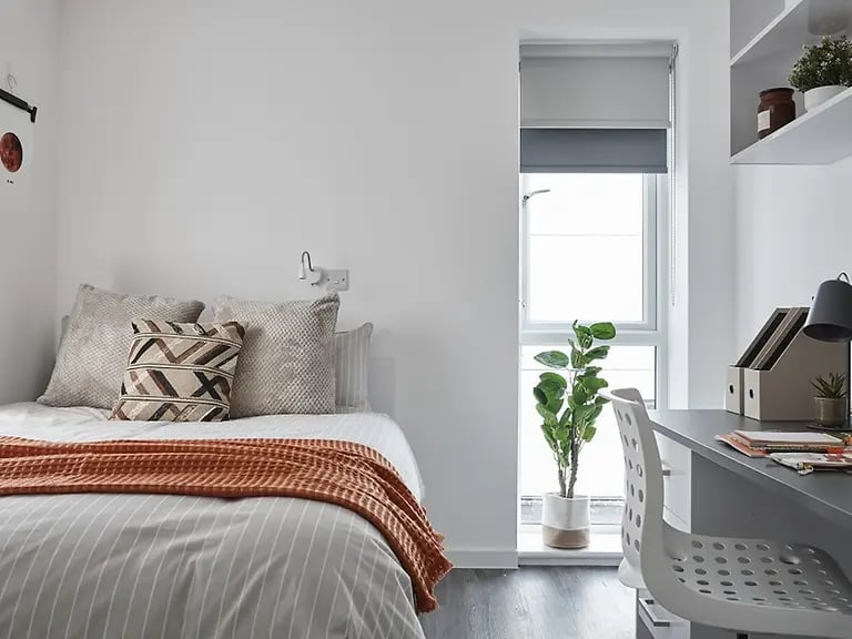 Bed with pillows and blanket desk and chair bedroom at The Quarry in Falmouth Student Accommodation