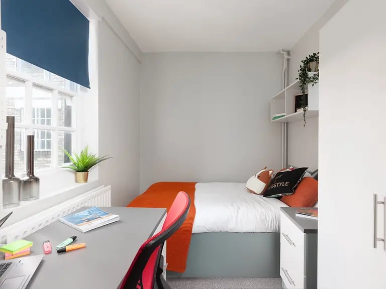 Bed desk chair pillows and shelving student bedroom at Louise House in London Student Accommodation