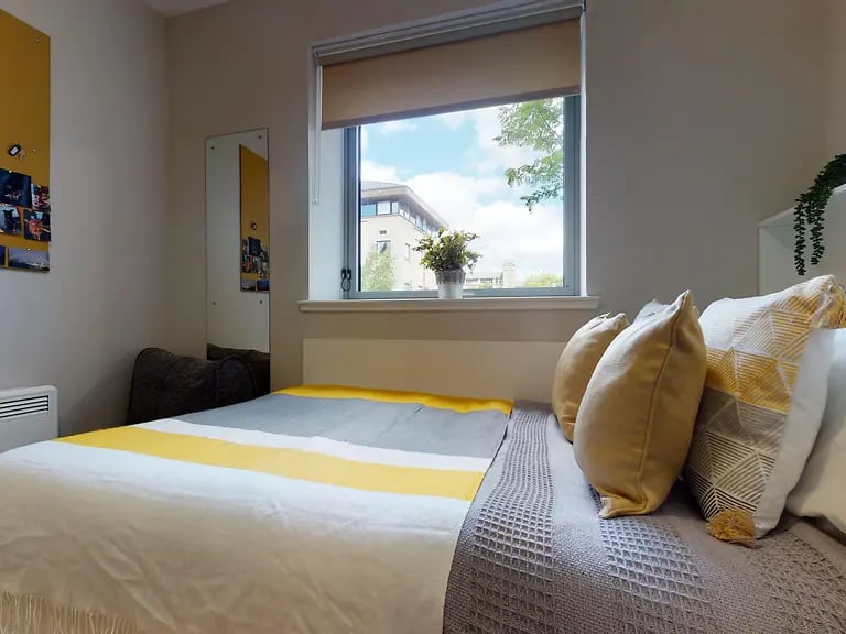 Bed with yellow grey bedding and pillows bedroom at Centro House in Stirling Student Accommodation