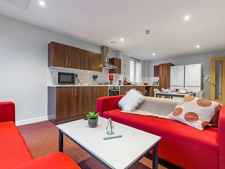 Red sofas white table kitchen area living room at Mary Parker House in Plymouth Student Accommodation