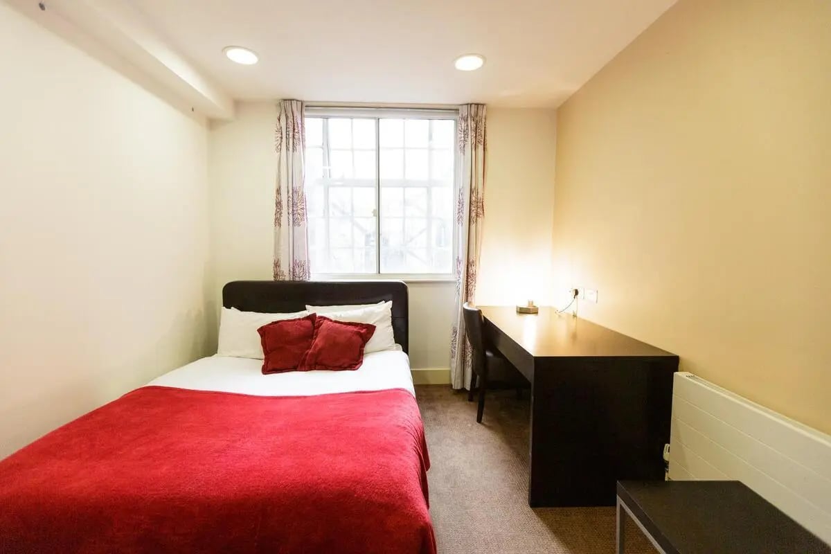 Bed with red blanket desk and chair bedroom at AXO Oxford Circus in London Student Accommodation