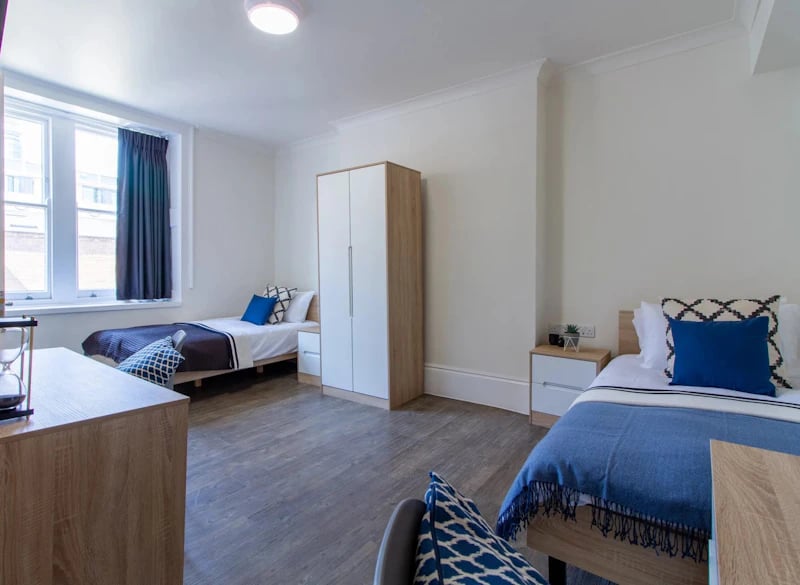 Two beds wardrobe and nightstands student bedroom at Bloomsbury Janet Poole House in London Student Accommodation