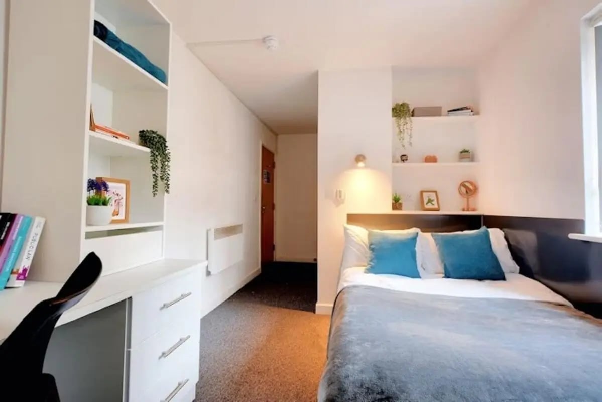 White desk with shelves bed with blue pillows bedroom at Newarke Street Leicester in Leicester Student Accommodation