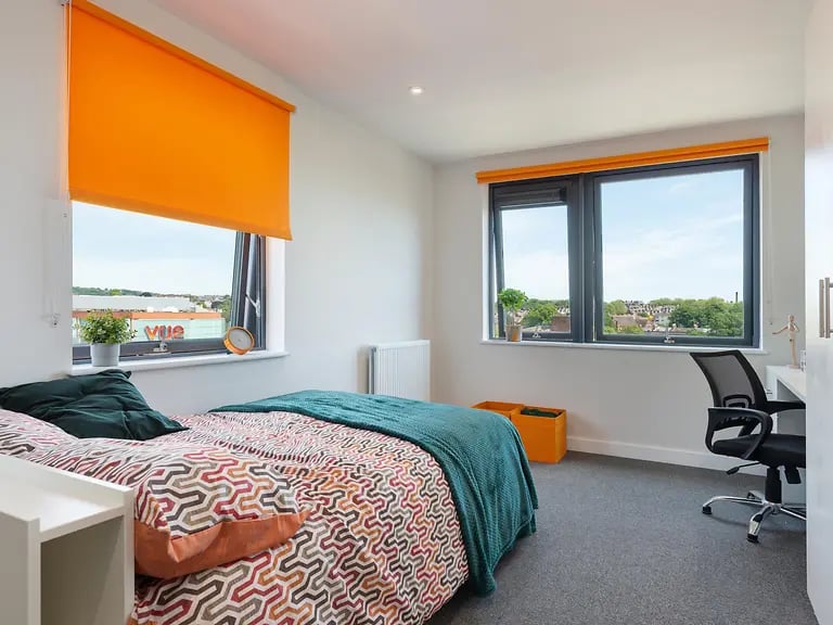 Bed desk chair window and orange blinds bedroom at Central Living in Exeter Student Accommodation