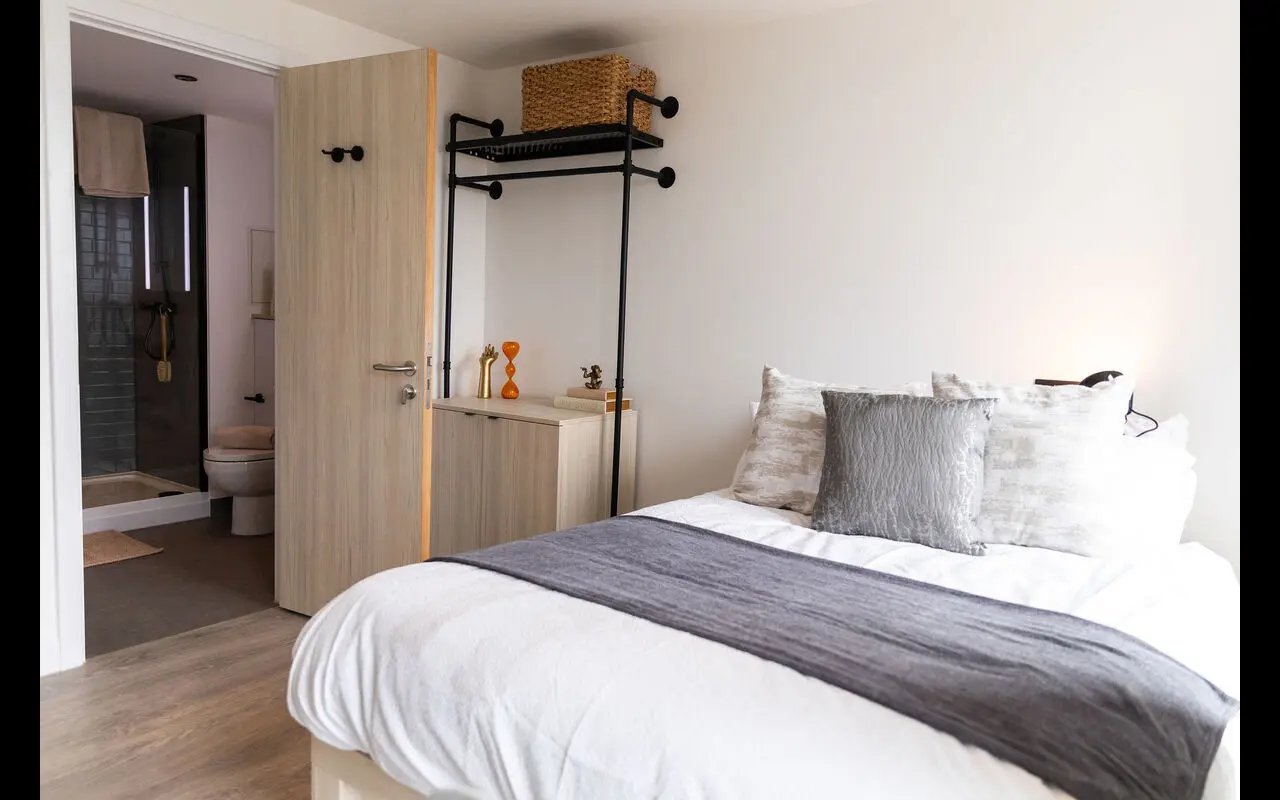 Bed with pillows shelf storage and bathroom bedroom at Martha Street Apartments in Glasgow Student Accommodation
