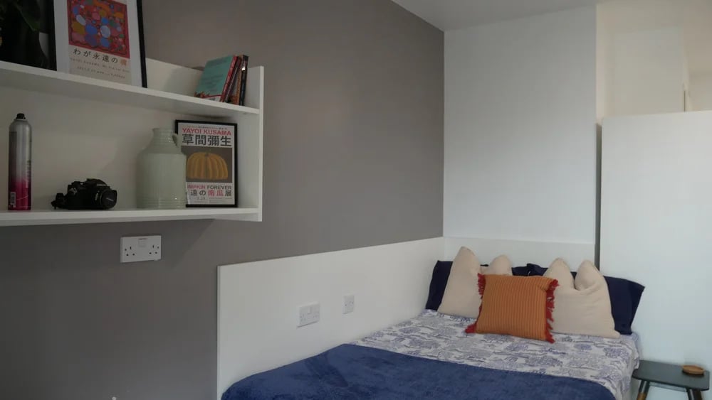Bed with decorative pillows and wall shelf Bedroom at Theatre House in Coventry Student Accommodation