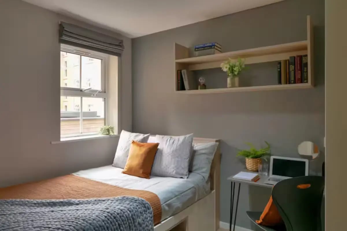 Bed with pillows desk with laptop study area at Emily Davies in Southampton Student Accommodation