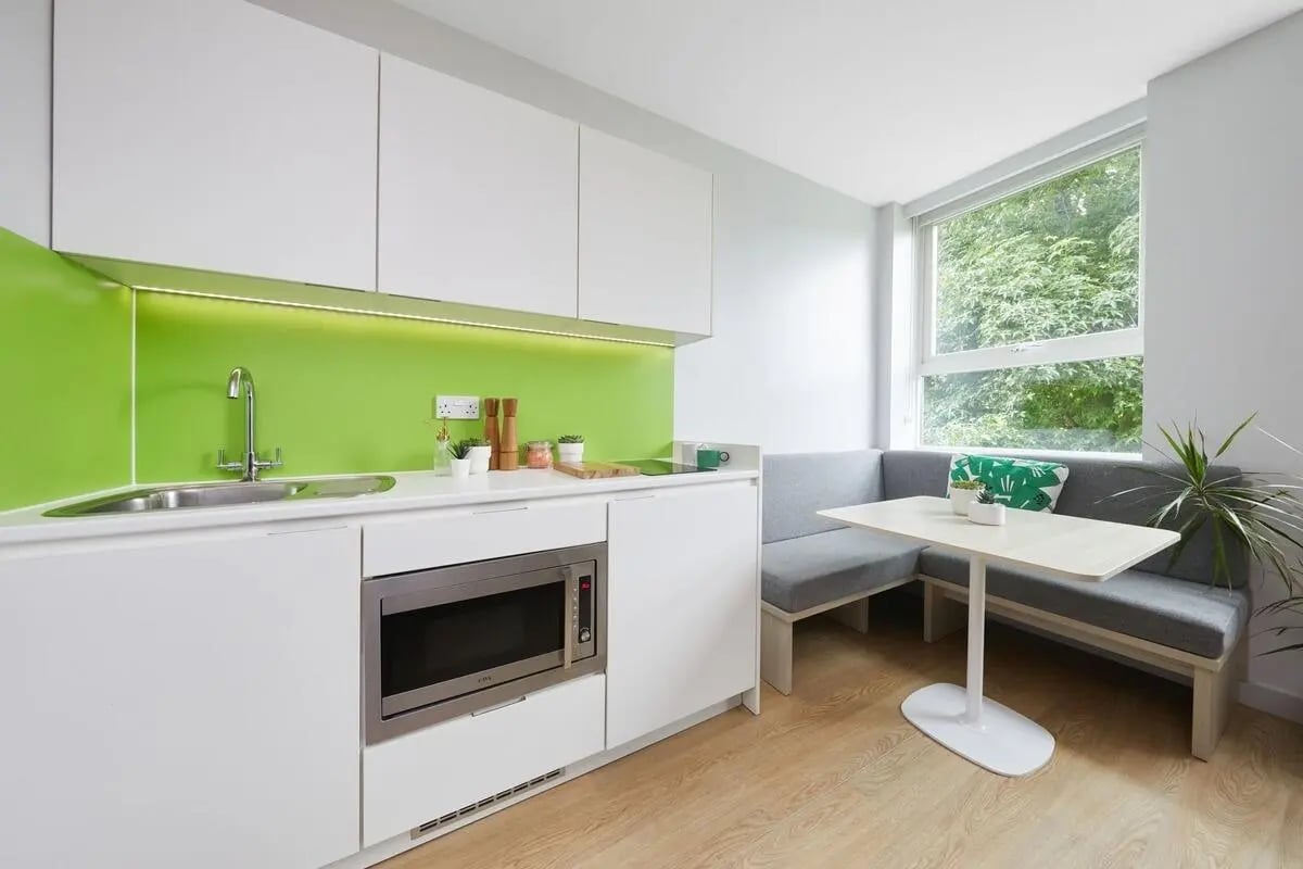White cabinets microwave sink green splashback kitchen bench seating area dining area kitchen at Collegiate Park House in Southampton Student Accommodation