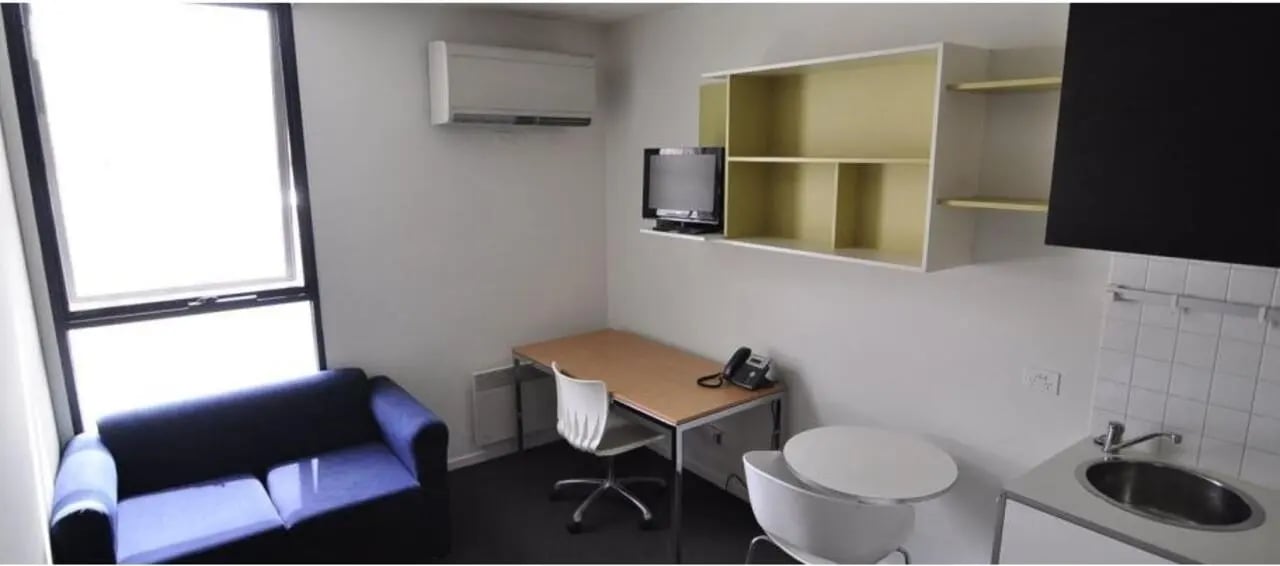 Sofa desk chair television shelves sink kitchen studio at Student Living On Campus in Melbourne Student Accommodation