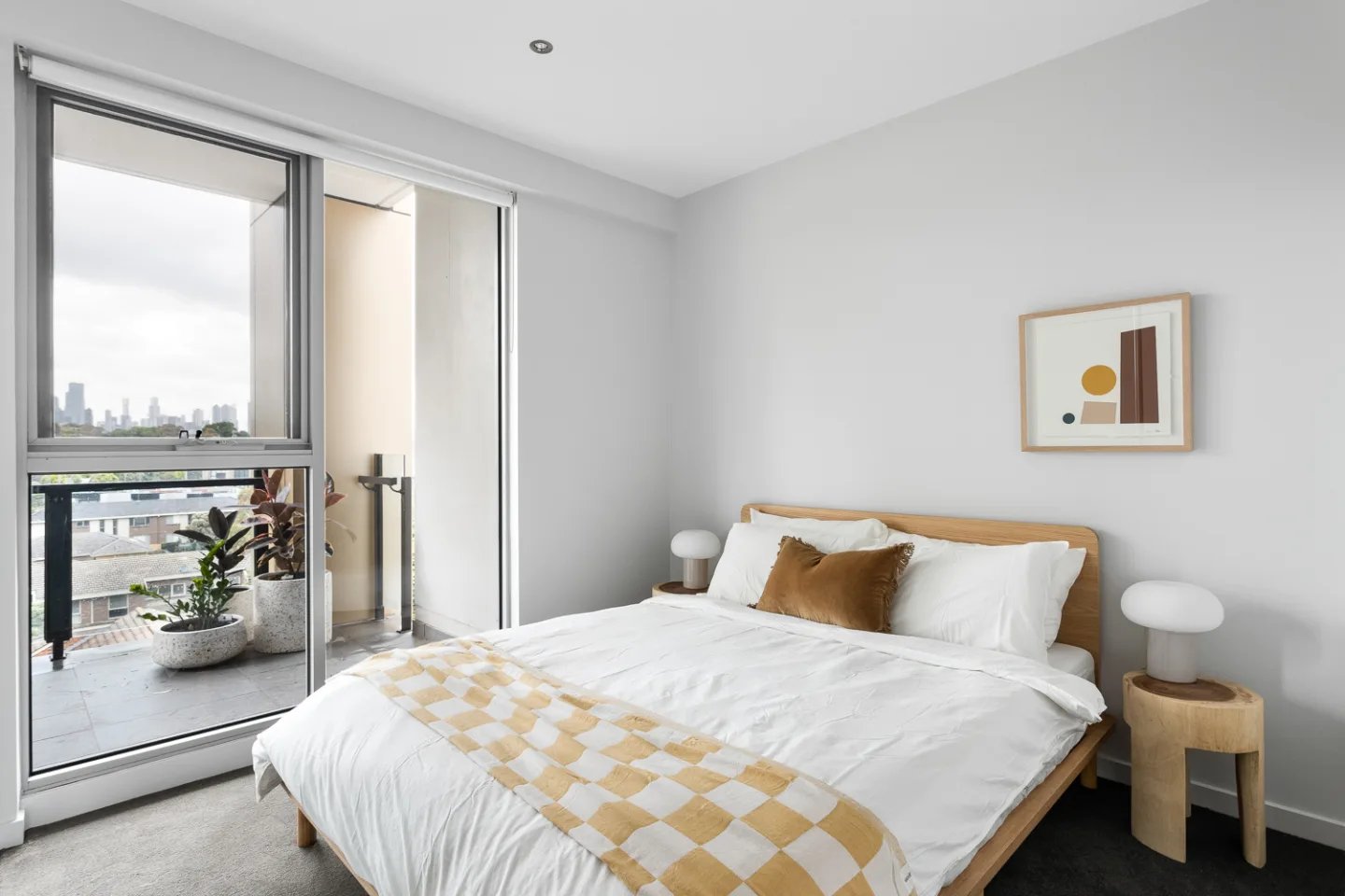White bed with brown pillow balcony plants bedroom at UKO Royal Park in Melbourne Student Accommodation