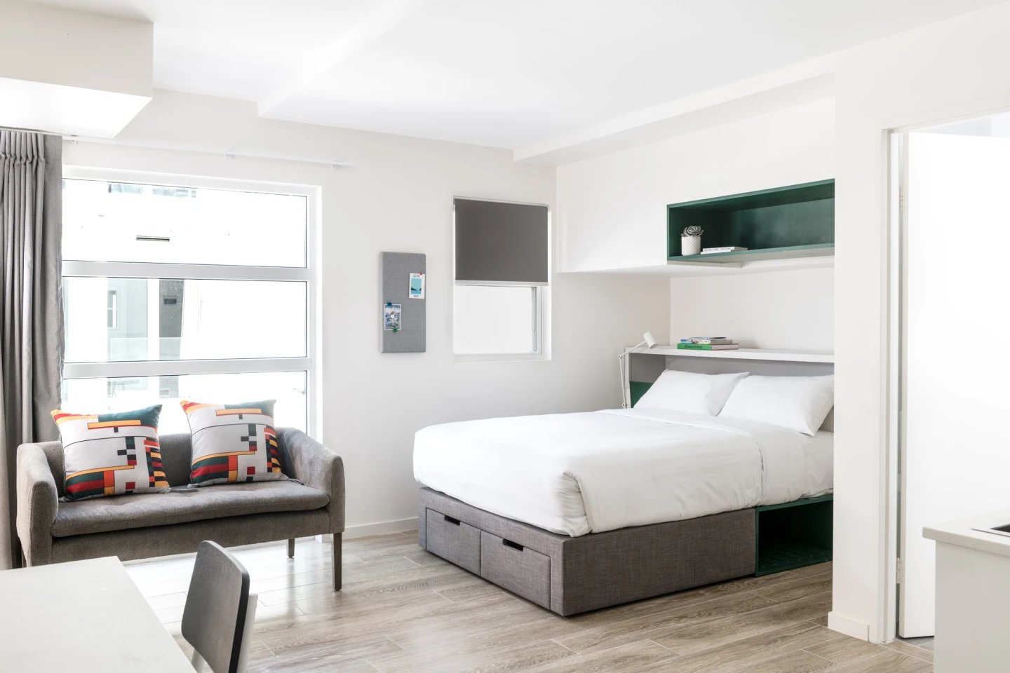 Grey sofa with patterned pillows bed with storage bedroom at UKO Stanmore in Sydney Student Accommodation