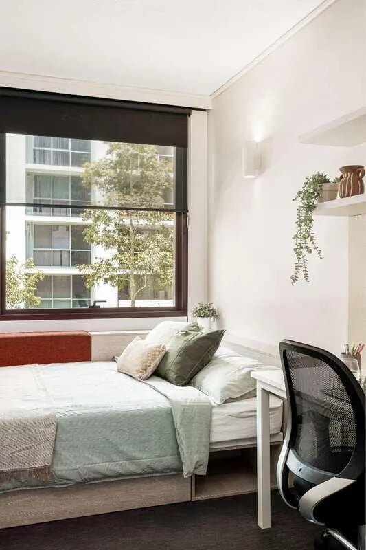 Bed with pillows window and desk bedroom at Iglu Mascot in Sydney Student Accommodation