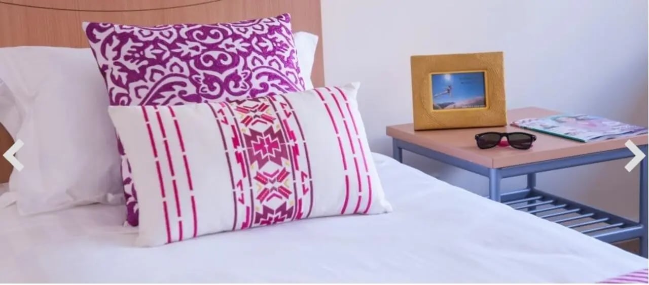 Bed with patterned pillows picture frame and sunglasses bedroom at Student Living-590 Lygon in Melbourne Student Accommodation