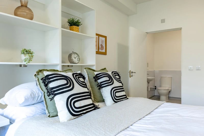 Bed with pillows shelves clock visible bathroom bedroom at St Augustine's House in Plymouth Student Accommodation