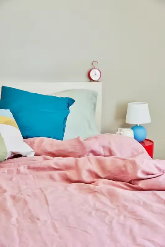 Bed with pink duvet teal pillows alarm clock bedroom at Scape Glebe in Sydney Student Accommodation