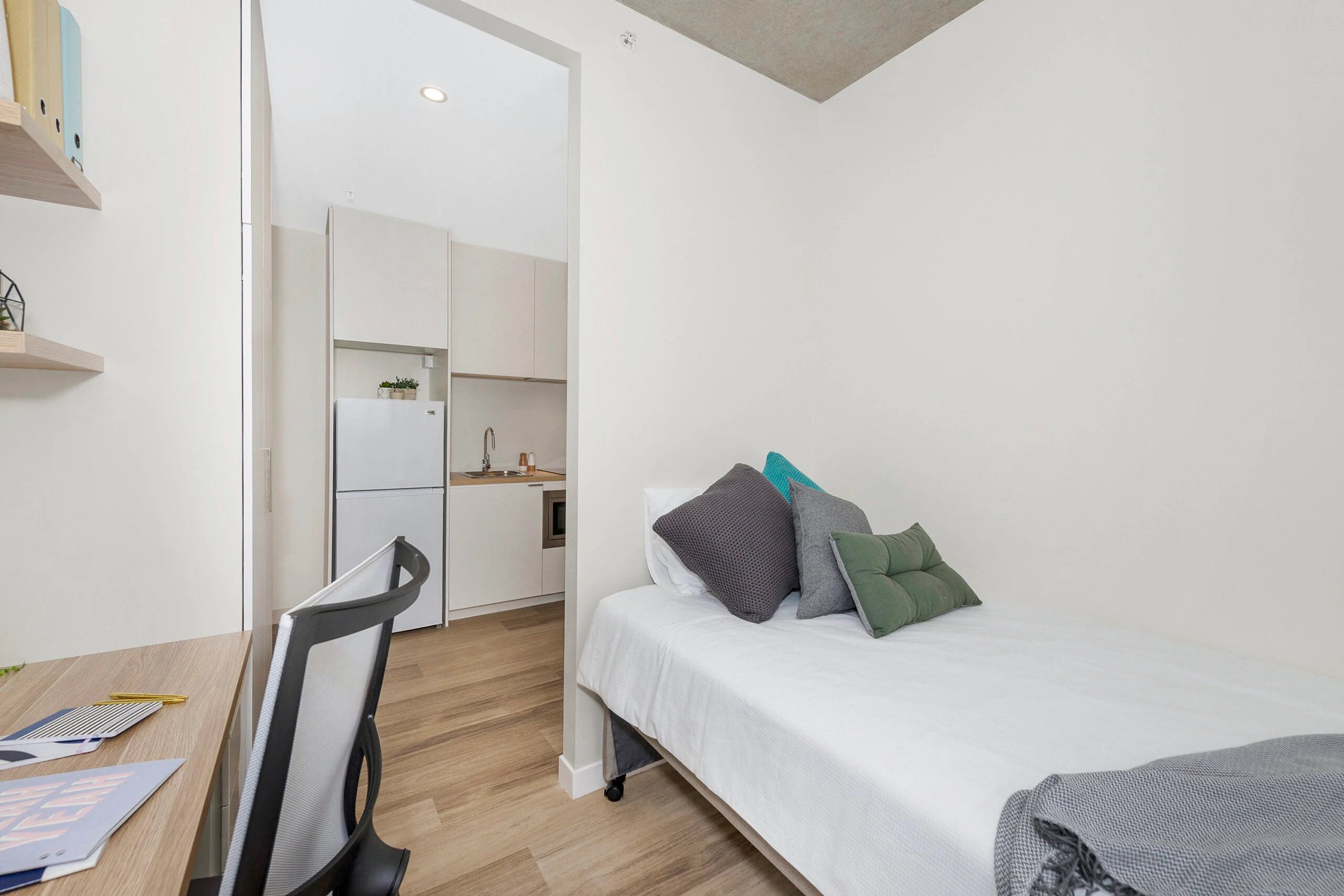 Bed desk chair and kitchen area bedroom at Scape St Lucia in Brisbane Student Accommodation