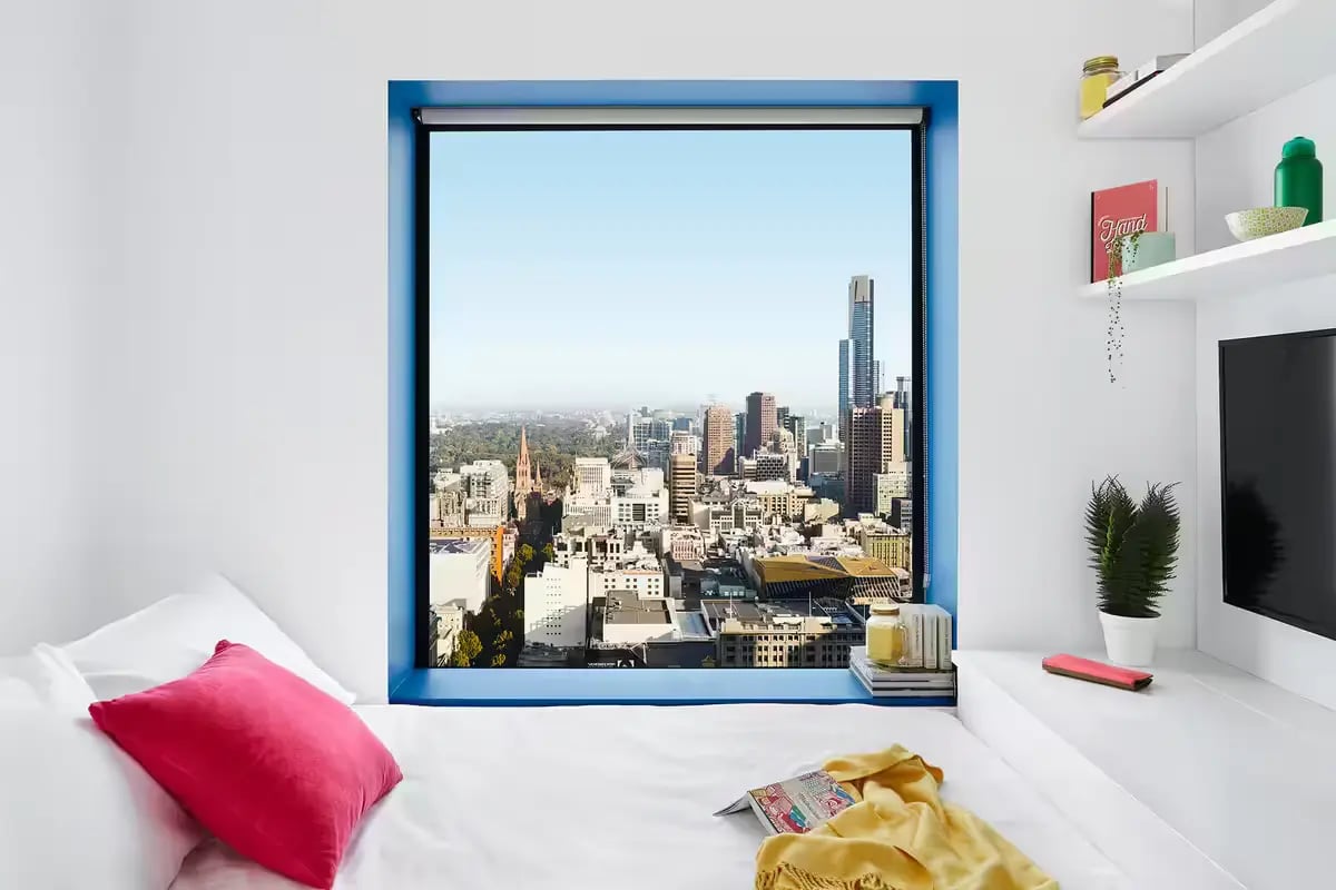 Bed pillows yellow blanket cityscape view bedroom at Scape Swanston in Melbourne Student Accommodation