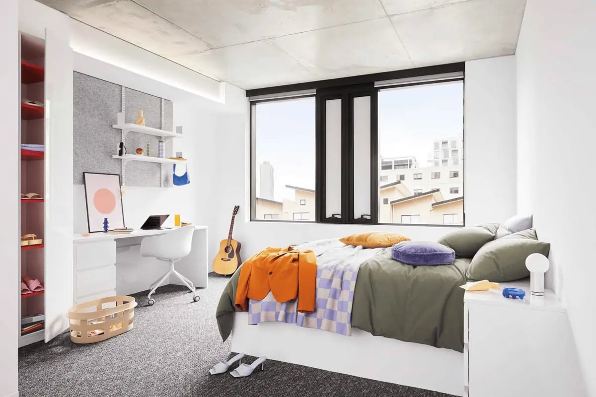 Bed desk shelving guitar and window bedroom at Scape Lincoln College in Melbourne Student Accommodation