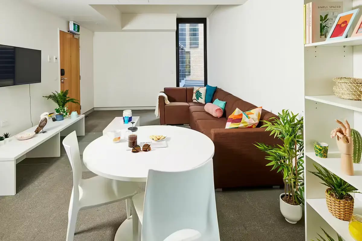 Sectional sofa with colorful cushions round dining table living room at Scape Cleveland in Sydney Student Accommodation