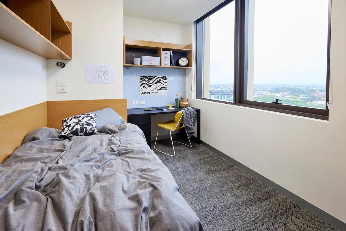 Bed desk chair shelves and large window bedroom at Scape Queensberry in Melbourne Student Accommodation