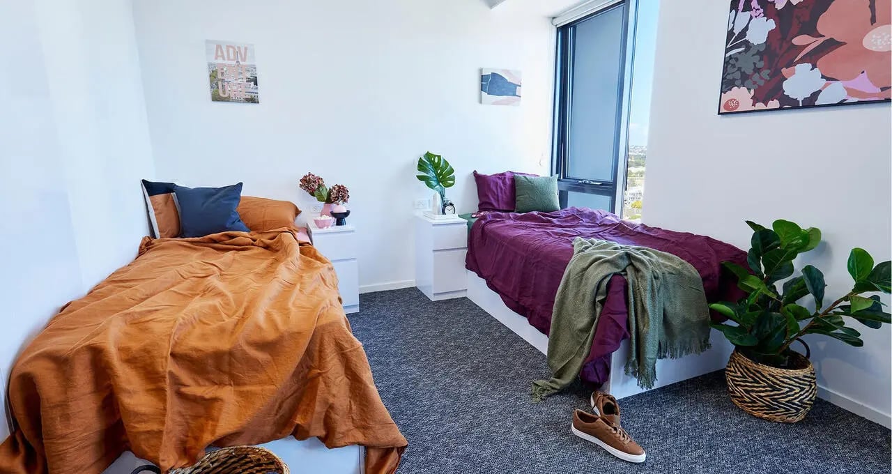 Two beds nightstands plants artwork bedroom at Scape Redfern in Sydney Student Accommodation