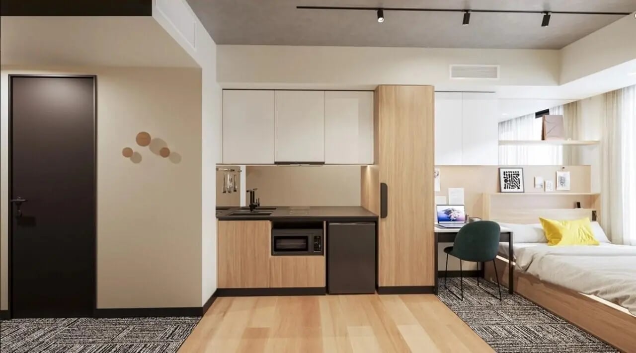 Kitchen desk bed and yellow pillow student studio at EPIISOD Macquarie Park in Sydney Student Accommodation