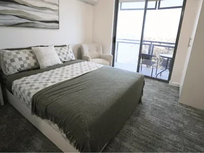 Bed armchair sliding door balcony table chairs bedroom at Student Living - Shafston in Brisbane Student Accommodation