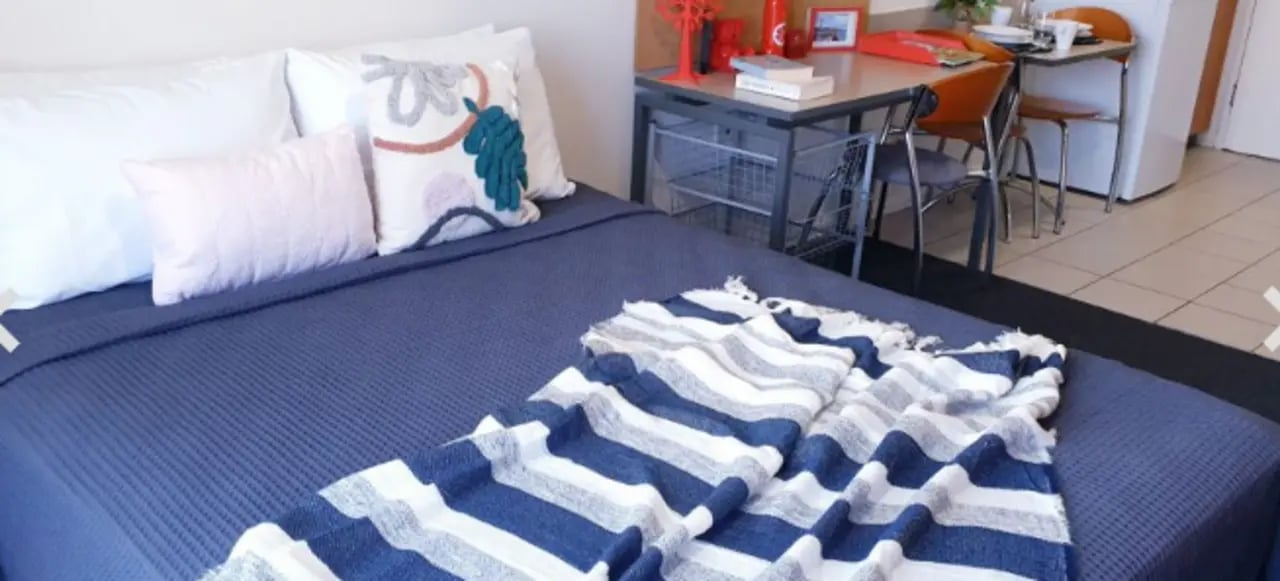 Bed with pillows throws desk chairs and fridge bedroom at Student Living - Shafston in Brisbane Student Accommodation