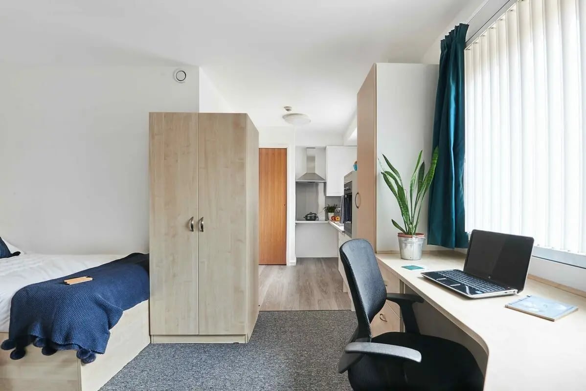 Bed desk wardrobe plant kitchen study area at Bernard Myers House in London Student Accommodation
