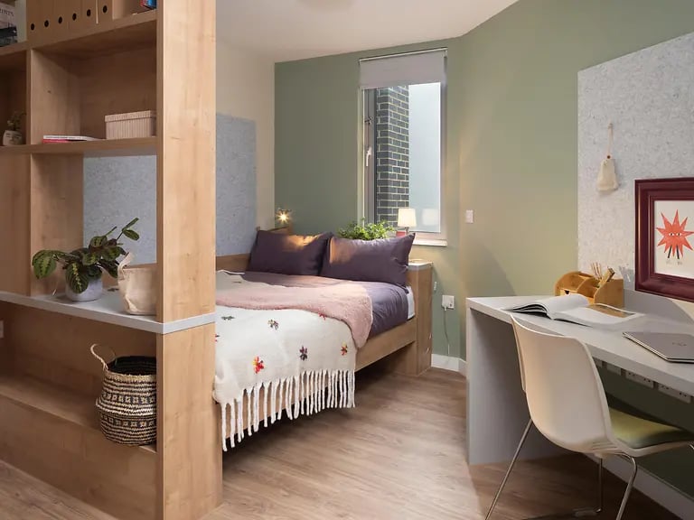 Bed desk shelves and plant student accommodation bedroom at The Curve in London Student Accommodation