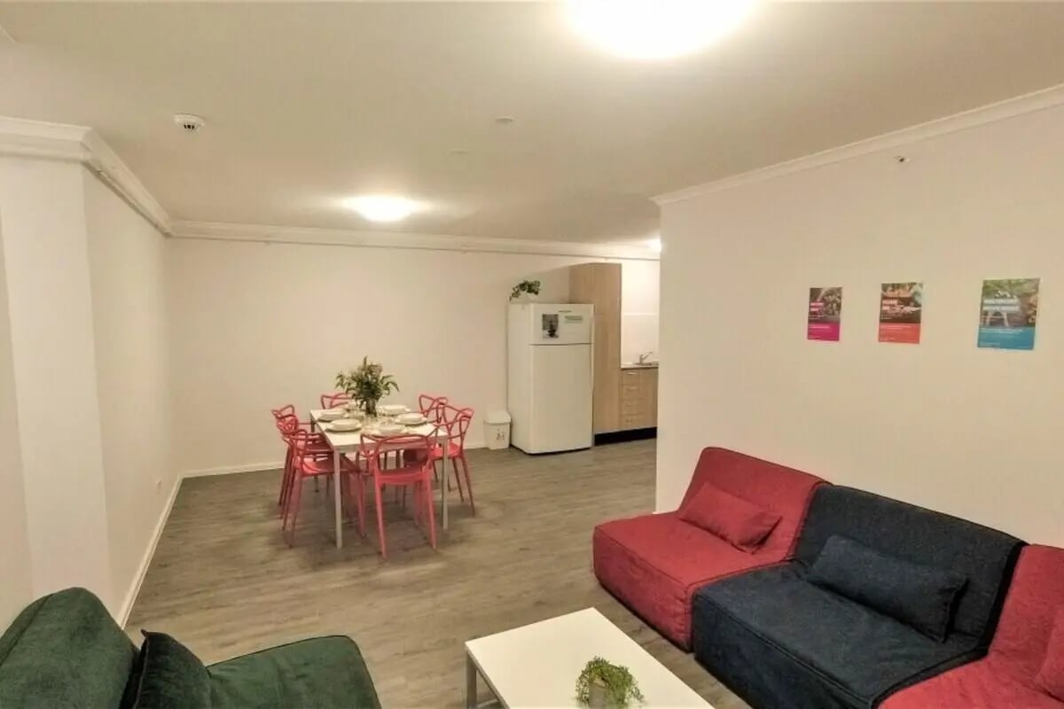 Dining table sofas refrigerator kitchen living area at Sydney University Village in Sydney Student Accommodation