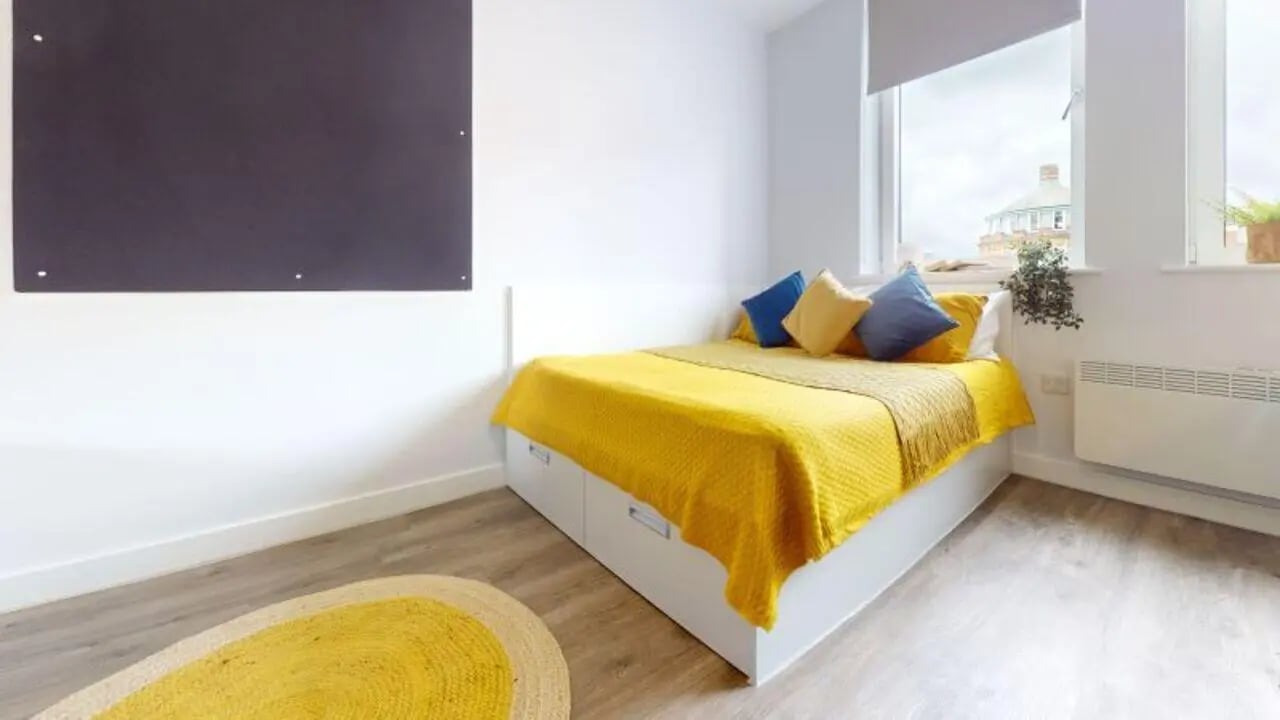 Bed with yellow covers and blue pillows bedroom at iQ Newland House in Nottingham Student Accommodation