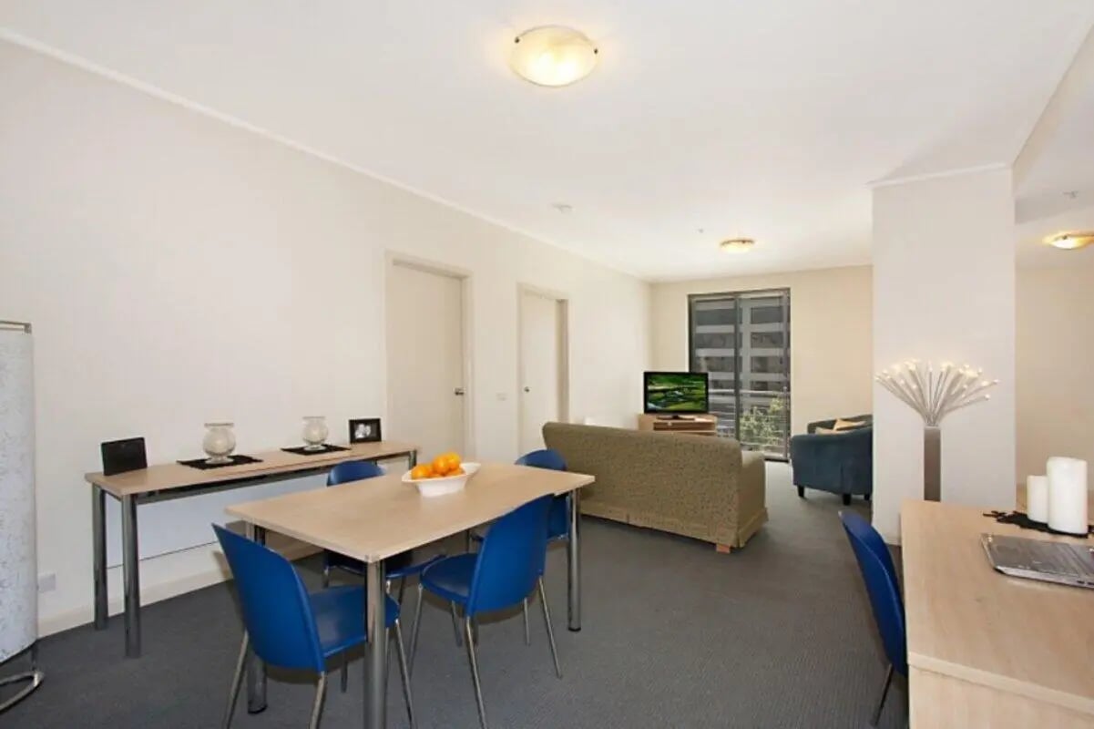 Dining table blue chairs sofa television living area at Student Living On ABeckett in Melbourne Student Accommodation