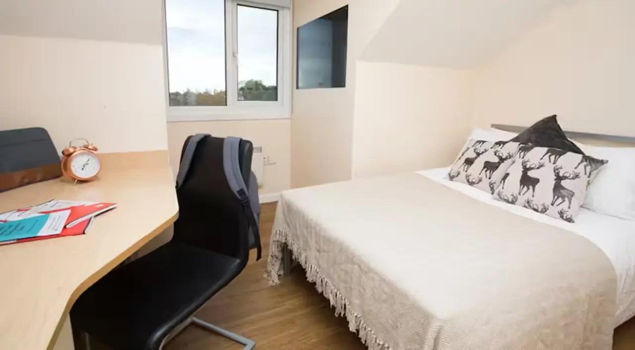 Desk with alarm clock and bed bedroom at Heald Court in Manchester Student Accommodation